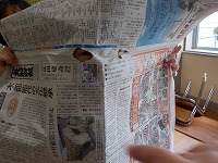 新聞紙から目を出して見ている子ども