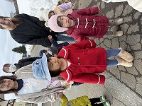 たんぽぽ組の子どもと手をつないで一緒に散歩をしているひまわり組の子ども