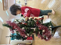 クリスマスツリーの飾りつけをする子ども