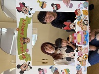 お父さんお母さんと一緒に記念撮影している誕生児