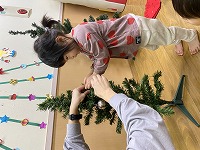 クリスマスツリーの飾りつけをする子ども