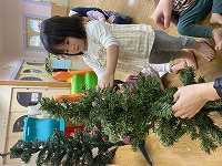 クリスマスツリーの飾りつけをする子ども