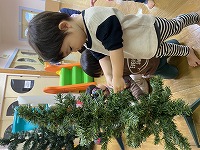 クリスマスツリーの飾りつけをする子ども