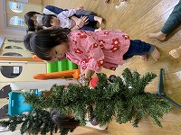 クリスマスツリーの飾りつけをする子ども