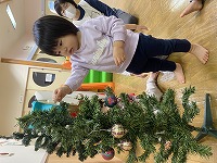 クリスマスツリーの飾りつけをする子ども