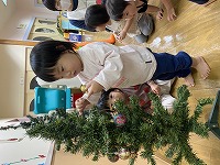 クリスマスツリーの飾りつけをする子ども