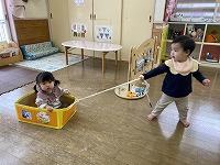 箱車に乗った友達を引っ張る女の子