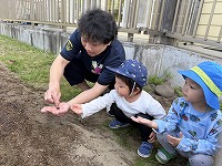 種を植えている先生と子どもたち