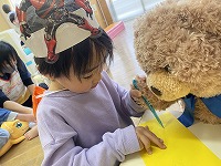 くまのぬいぐるみと一緒にお絵描きを楽しむ子ども
