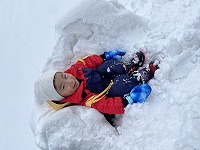 雪の塊をイスに見立てて座る子ども