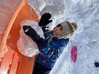 そりに雪の塊を乗せる子ども