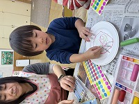コマの紙皿に飾り付けをしている子ども