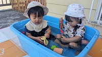 女の子二人でタライの水に浸かって涼んでいます