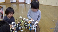 洗濯ばさみをかごにはさんで遊んでいる子ども