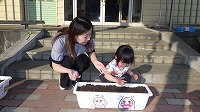 お母さんと女の子が種をまいている