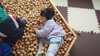 木のボールプールで遊ぶ女の子