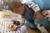 座ってボードの玩具に触れている男の子