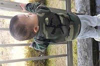 柵につかまり立ちする男の子の後ろ姿