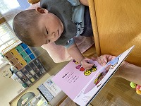 絵本を指差し、難しい顔をする男の子の赤ちゃん