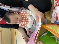 保育士に絵本を読んでもらっている１０カ月の女の子