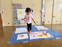 立ちながらダイナミックに筆を使ってお絵描きしている女の子