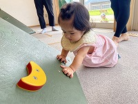 木の玩具に興味を示して触っている８ヶ月女児