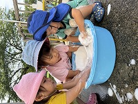 タライに入っている大量の泡をかき混ぜている子ども達