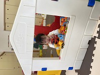 おうちサークルの窓で車を並べて遊ぶ女の子