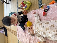 ねんねしている友達の顔を覗き込む女児