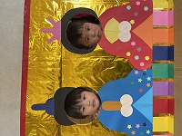 お内裏様とお雛様の顔パネルで２ショットを撮る子ども