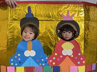 お内裏様とお雛様の顔パネルで２ショットを撮る子ども