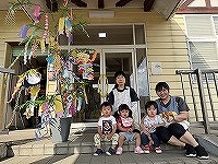 笹飾りの前で笑顔の先生と子どもたち