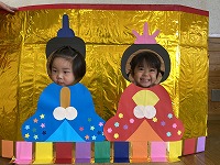 お内裏様とお雛様の顔パネルで２ショットを撮る子ども