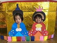 お内裏様とお雛様の顔パネルで２ショットを撮る子ども