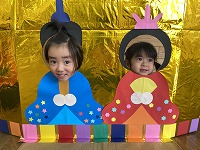 お内裏様とお雛様の顔パネルで２ショットを撮る子ども