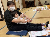 ママの膝の上でマッサージをうける赤ちゃん