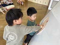 ケーキにクリームとイチゴのイラストを貼る子ども
