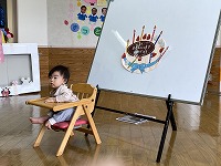 完成したケーキの前で誕生児が写真撮影
