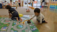 ひまわり組の子どもとミニカーで遊んでいる子ども