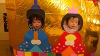 お内裏様とお雛様の顔パネルで２ショットを撮る子ども