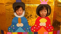 お内裏様とお雛様の顔パネルで２ショットを撮る子ども