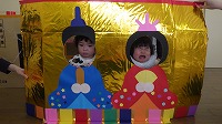 お内裏様とお雛様の顔パネルで２ショットを撮る子ども