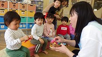 先生からかぶとの折り紙をもらって喜んでいる子ども達