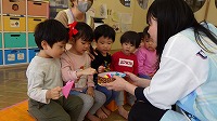 先生からかぶとの折り紙をもらって喜んでいる子ども達