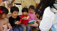 先生からかぶとの折り紙をもらって喜んでいる子ども達