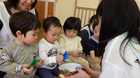 先生からかぶとの折り紙をもらって喜んでいる子ども達