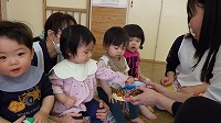 先生からかぶとの折り紙をもらって喜んでいる子ども達