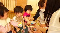 先生からかぶとの折り紙をもらって喜んでいる子ども達