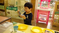 トングでお魚をつかまえようとしている男の子