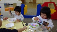 食べ物に見立てたフラワーブロックを別の容器に移し替えている男の子と女の子